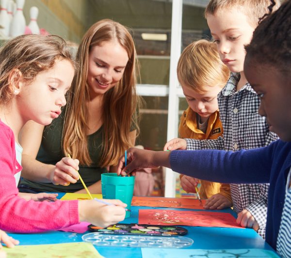 Kinder und Lehrerin malen mit Wasserfarbe