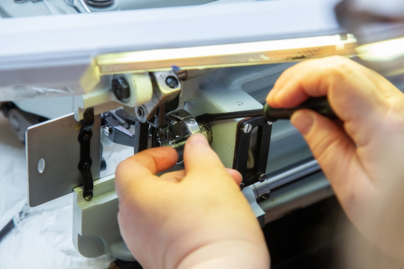 Frauenhände beim Reparieren einer Nähmaschine