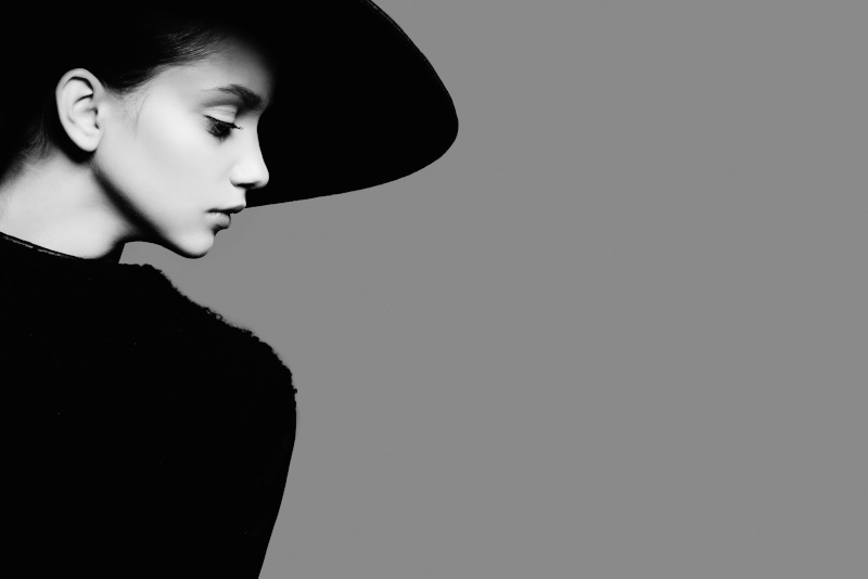 Porträt einer jungen Frau mit schwarzem Hut und schwarzem Pulli