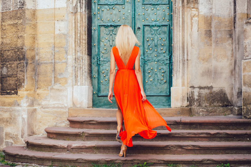 Blonde Frau in orangefarbenem Kleid